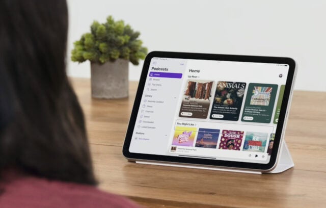 iPad Air 13 inch on a table. To the side of the image is the back of a person's head. The person is looking at the iPad.